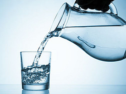 Ein Wasserkrug schüttet Wasser in ein Glas