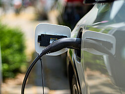 Weißes Elektroauto hängt am Ladekabel