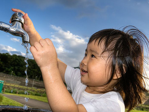 Ein Kind dreht einen Wasserhahn auf