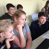 Schüler und Schülerinnen vor ihrem gemeinsamen Computer.