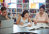 Ein Schüler und zwei Schülerinnen erledigen ihre Hausübung