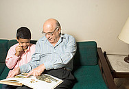 Ein Senior liest einem Kind ein Buch vor.