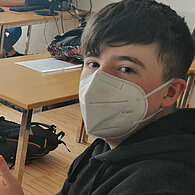 Schüler mit FFP2-Maske streckt den Daumen nach oben 