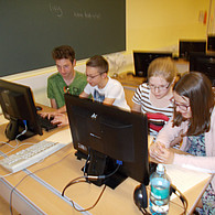 2 Schülerinnen und zwei Schüler sitzen vor zwei Computern im Klassenzimmer